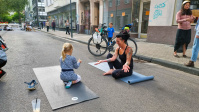 Eine Frau macht mit einem Kind Yogaübungen auf der Sommerstraße.