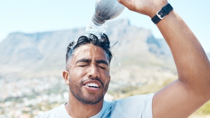 Mann schüttet sich eine Flasche Wasser über den Kopf - Tipps gegen Hitze