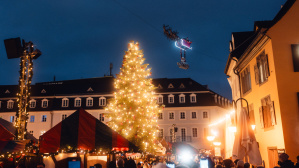 Christkindl-Markt auf dem St. Johanner Markt mit großem geschmücktem Tannenbaum und dem fliegenden Weihnachtsmann darüber