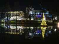 Nachtaufnahme des Deutschmühlenweihers mit einem beleuchteten Tannenbaum, der sich im Wasser spiegelt