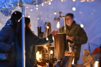 Frauen vor und hinter weihnachlichem Verkaufsstand mit Holzwaren - dekoriert mit Lichterketten