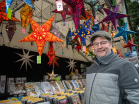 Verkäufer vor einem Stand mit Sternlampions und Schildern