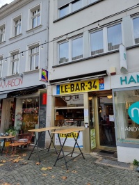 Außenansicht der Austernbar Le Bar 34 mit Namensbanner, davor sind zwei Stehtische