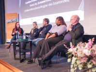 Menschen auf einem Podium vor der Leinwand im Filmhaus Saarbrücken