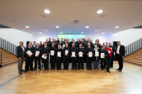 Eine Gruppe Personen in Uniform steht in Reihen und hält weiße Mappen fest