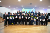 Eine Gruppe Personen in Uniform steht in Reihen und hält weiße Mappen fest