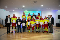 Eine Gruppe Personen in Uniform steht in Reihen und hält weiße Mappen fest