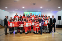 Eine Gruppe Personen in Uniform steht in Reihen und hält weiße Mappen fest